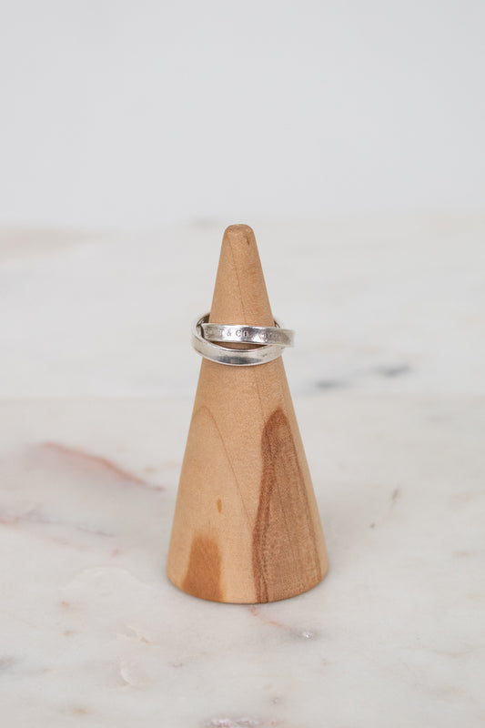 Silver ring on a wooden ring stand against a marble background