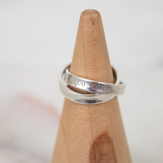 Silver ring on a wooden ring stand with a blurred background