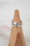 Silver ring on a wooden ring stand with a blurred background