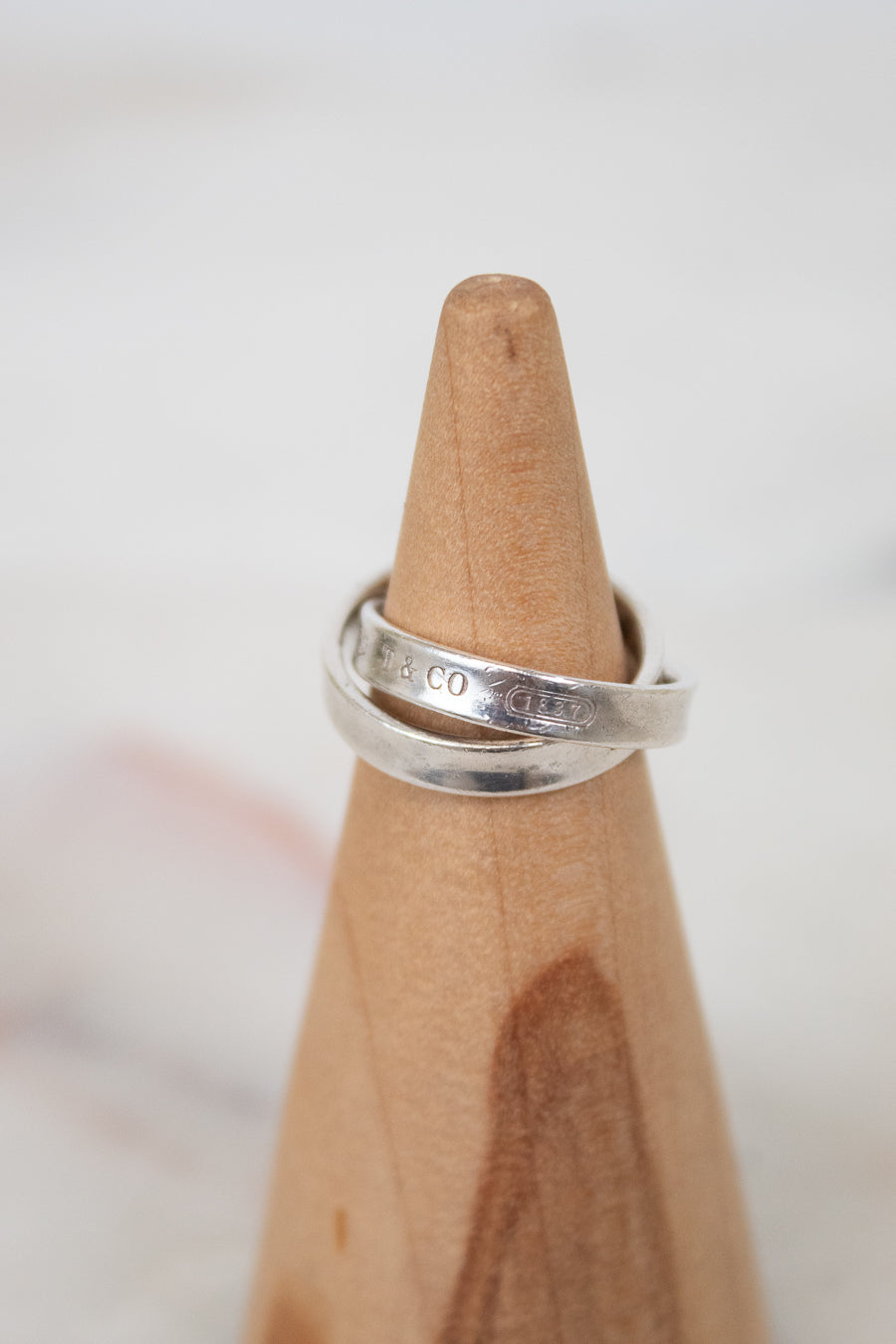 Silver ring on a wooden ring stand with a blurred background