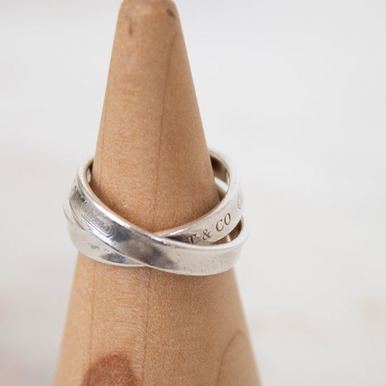 Silver ring on a wooden ring stand with a white background