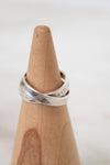 Silver ring on a wooden ring stand with a white background