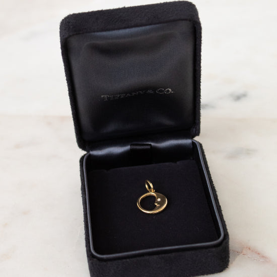 Gold pendant in a Tiffany & Co. jewelry box on a marble surface