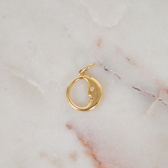 Gold pendant with a small diamond on a marble surface