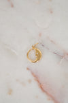 Gold pendant with a small diamond on a marble surface