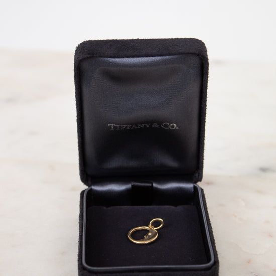 Gold pendant in a black Tiffany & Co. jewelry box on a marble surface