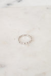 A delicate silver beaded ring resting on a light beige marble surface.