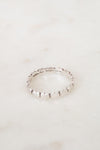 A delicate sterling silver beaded ring resting on a light beige marble surface. The inner band is engraved with 'TIFFANY & CO '.