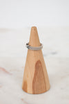 Wooden cone-shaped ring holder with a silver ring on a white background
