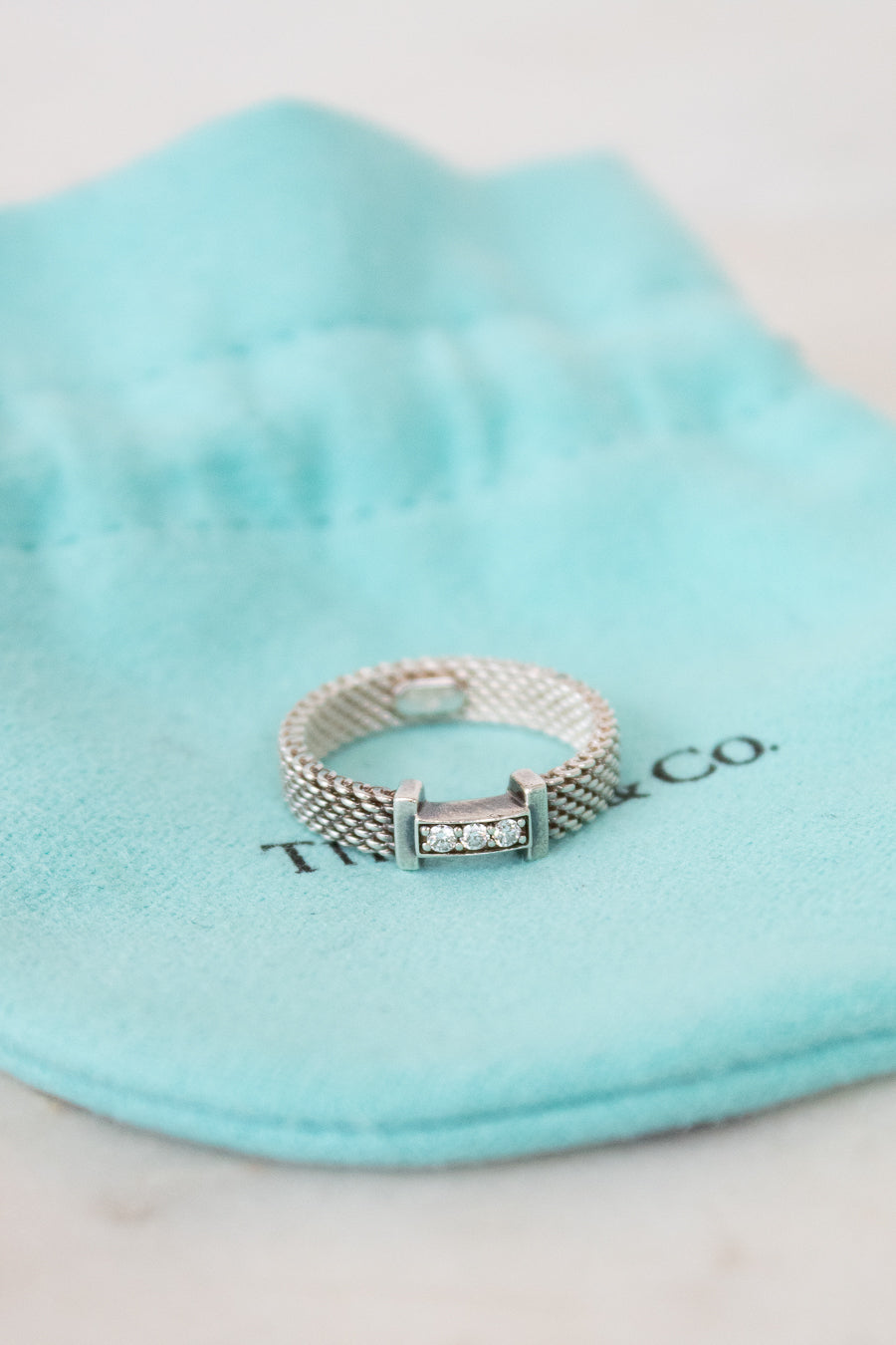 Silver ring with diamonds on a Tiffany & Co. branded pouch
