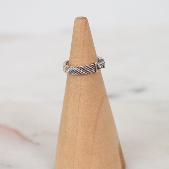 Silver ring on a wooden cone against a white background