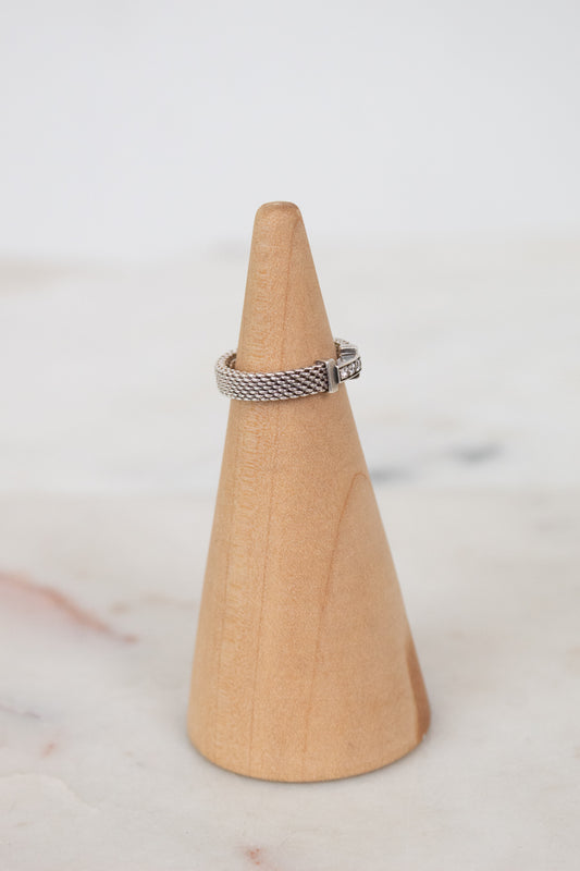 Silver ring on a wooden cone against a white background