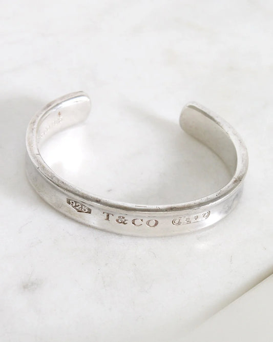 Silver bracelet with 'T&CO' engraving on a marble surface