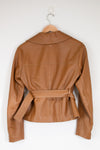A tan leather jacket with a collar and matching waist belt, hanging on a wooden hanger against a plain white wall.