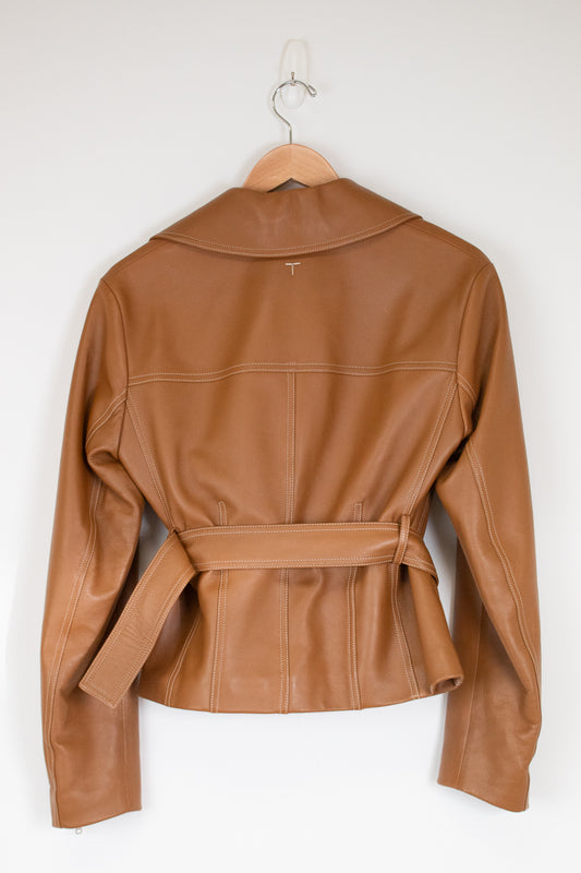 A tan leather jacket with a collar and matching waist belt, hanging on a wooden hanger against a plain white wall.