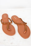 A pair of tan leather flat thong sandals with braided rope straps and gold-tone metal accents, displayed on a white marble surface.