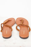 A pair of TOM FORD flat thong sandals in tan leather with braided brown straps and gold-tone hardware, shown from a top-down view on a white marble surface.