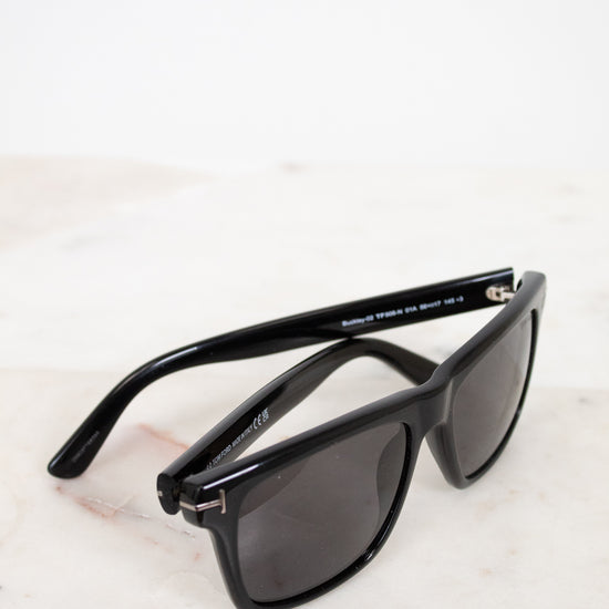 Black sunglasses with dark lenses on a light marble surface