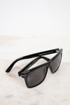 Black sunglasses with dark lenses on a light marble surface