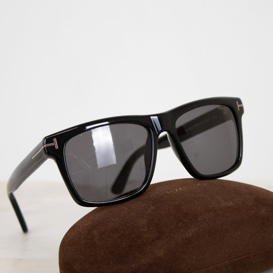 Black sunglasses with dark lenses on a brown case against a light background