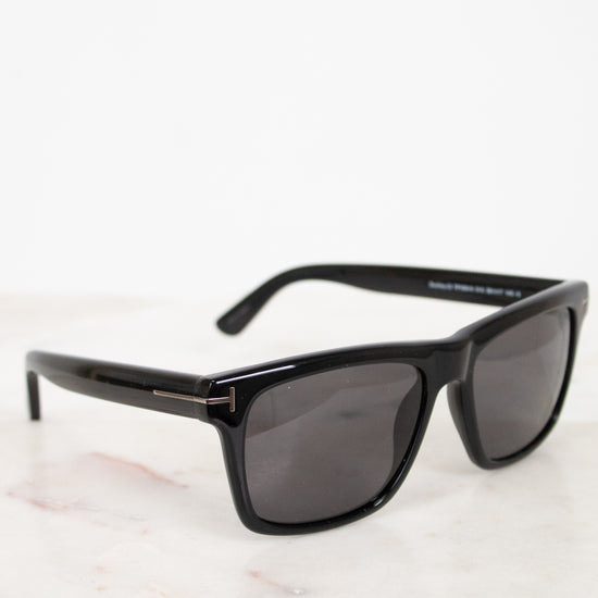 Black sunglasses with dark lenses on a light marble surface