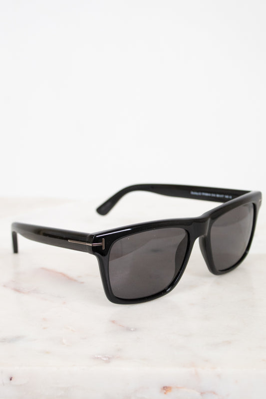 Black sunglasses with dark lenses on a light marble surface