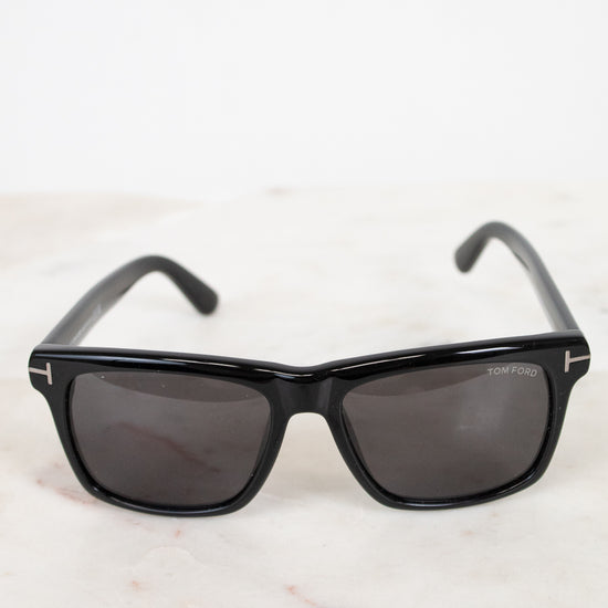 Black sunglasses with dark lenses on a light marble surface