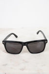 Black sunglasses with dark lenses on a light marble surface
