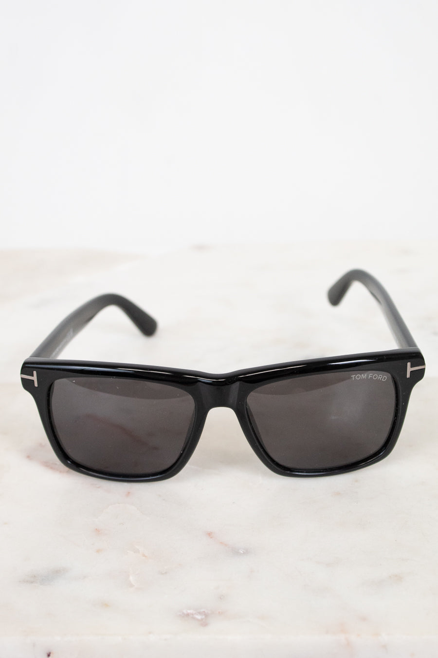 Black sunglasses with dark lenses on a light marble surface