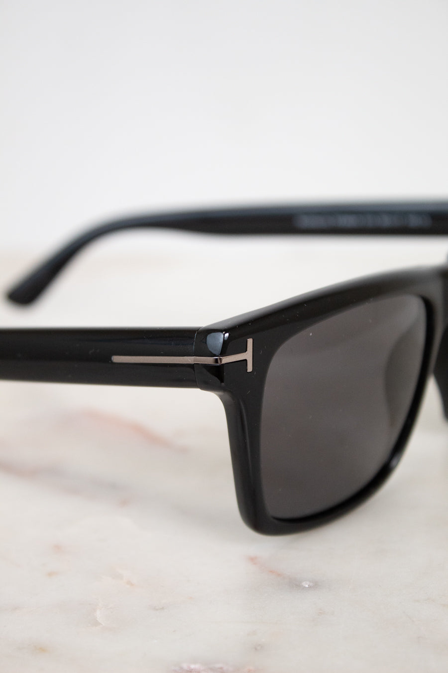 Black sunglasses with a visible brand logo on a light background