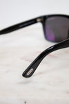 Black sunglasses with a brand logo on a light marble surface