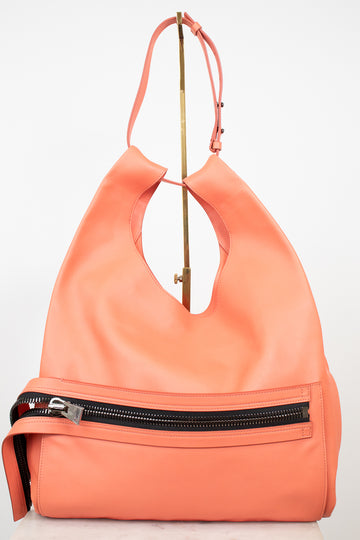A coral orange leather shoulder bag with a front zippered pocket and a gold-tone metal stand, photographed against a plain white background.