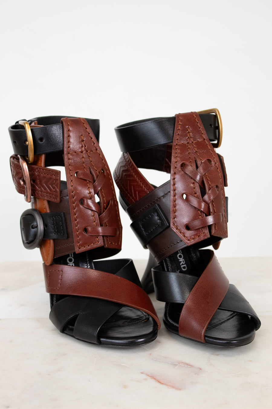 Pair of brown and black leather sandals on a white background