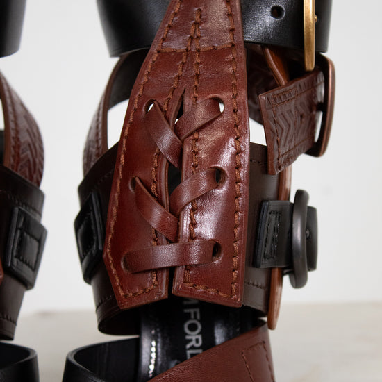 Close-up of a black leather shoe with a brown leather strap on a white background