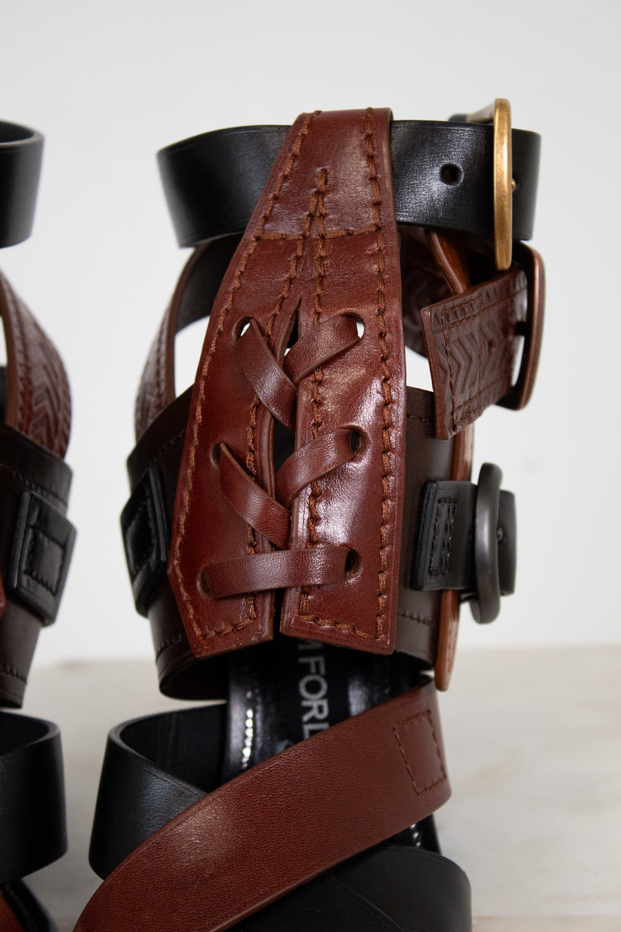 Close-up of a black leather shoe with a brown leather strap on a white background