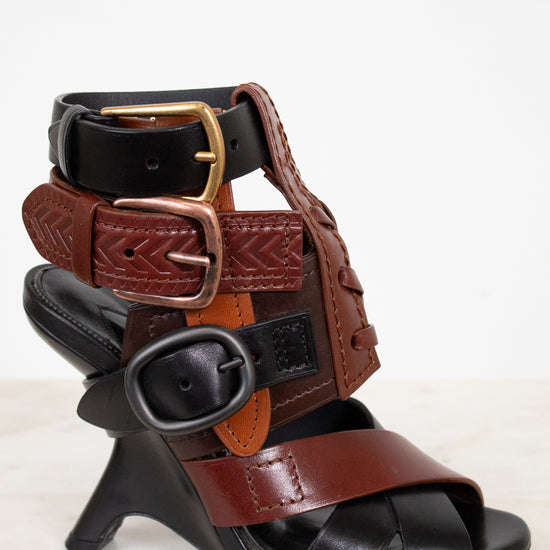 Black and brown leather sandal with decorative straps on a white background