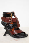 Black and brown leather sandal with decorative straps on a white background