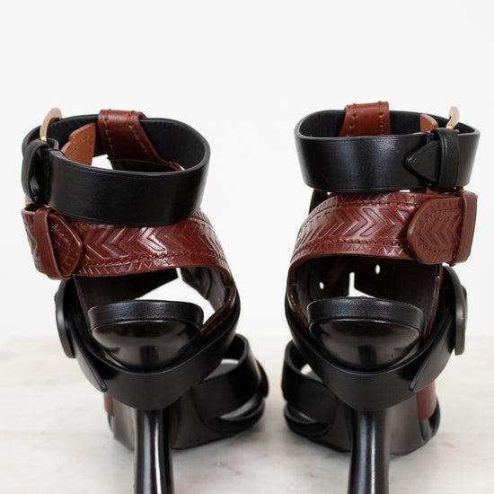 Pair of black and brown high-heeled sandals on a white background