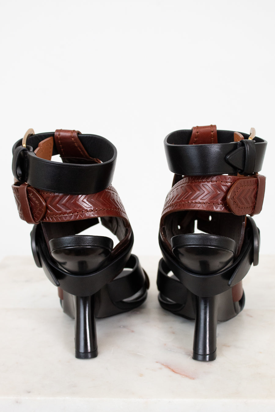 Pair of black and brown high-heeled sandals on a white background