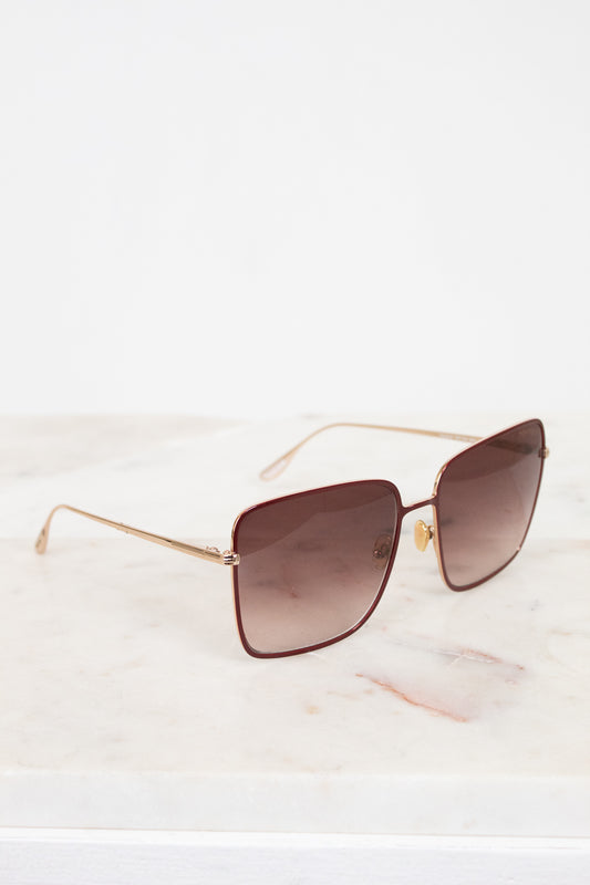 Sunglasses with gold frame and brown lenses on a white background