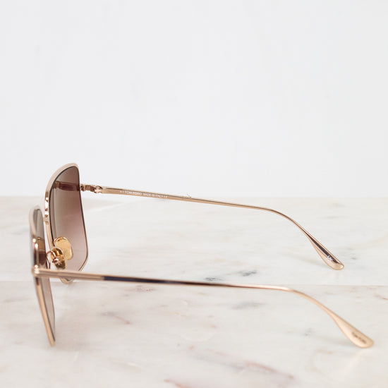 Gold-framed sunglasses on a marble surface