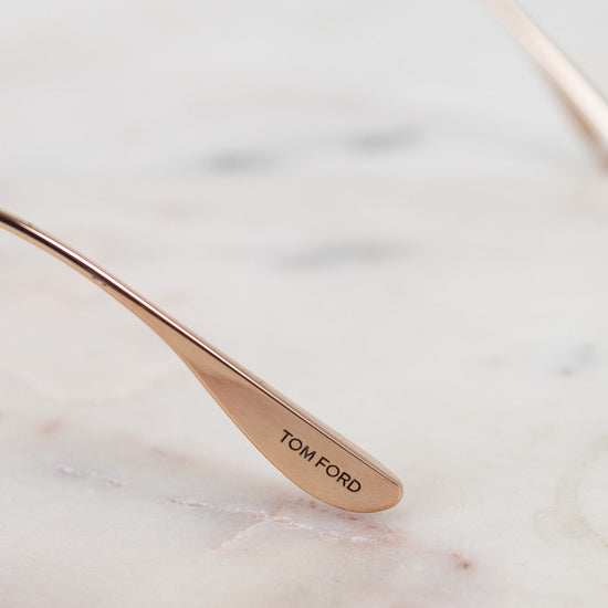 Rose gold spoon with 'Tom Ford' engraving on a marble surface