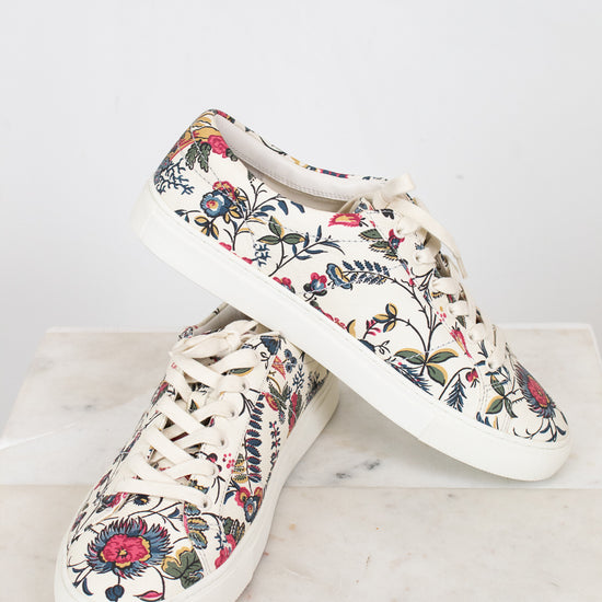 Floral-patterned sneakers on a marble surface with a white background