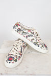Floral-patterned sneakers on a marble surface with a white background