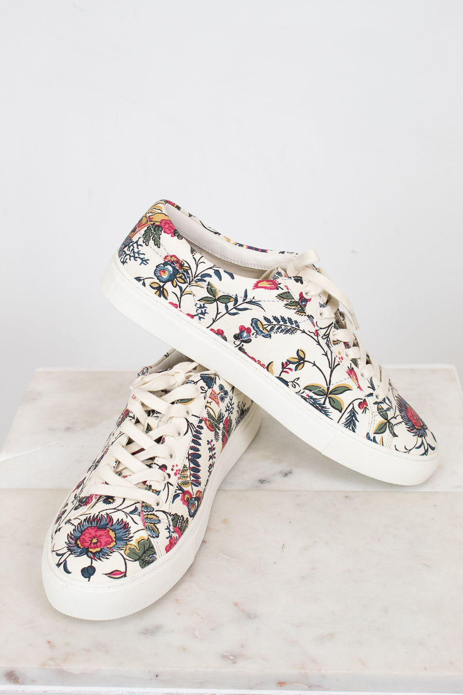Floral-patterned sneakers on a marble surface with a white background
