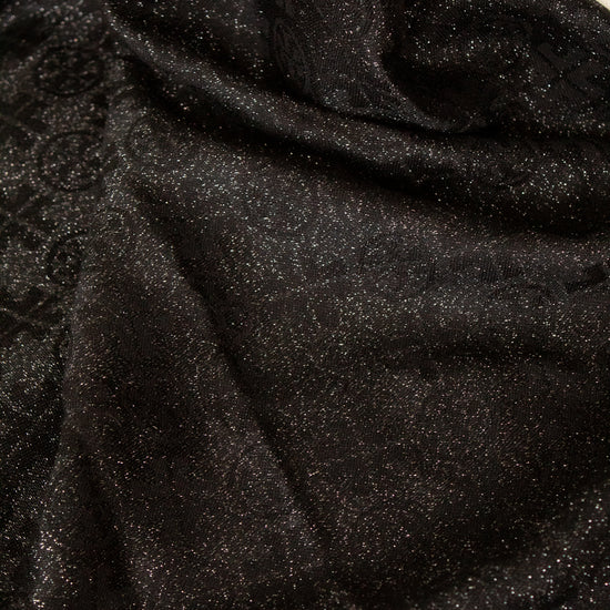 A close-up of draped black fabric with a subtle glittery texture against a white background visible at the top edge.