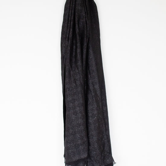 A black textured scarf with fringed edges, draped vertically against a plain white background.