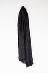 A black textured scarf with fringed edges, draped vertically against a plain white background.