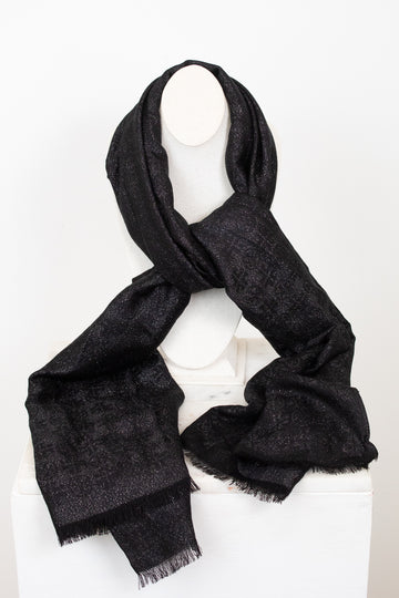 A black textured scarf with subtle shimmer and fringed edges, draped on a white canvas bust against a plain white background.