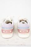 A pair of Tory Burch low-top sneakers shown from the back, featuring lavender suede, light blue suede, cream canvas, and pink stripe accents on the heel.